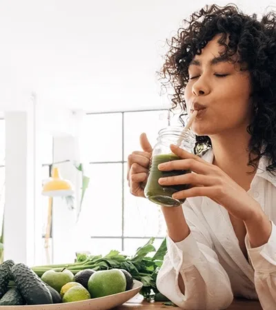 a girl sitting at a table with a bowl of fruit and a bottle of water