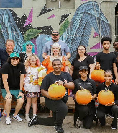 a group of people posing for a photo with pumpkins