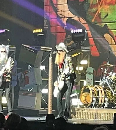 Rock band performing live on stage with colorful graffiti backdrop and bright stage lights