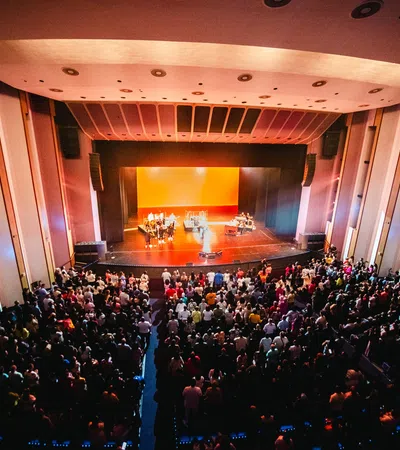 a large group of people in a room with a stage and a large audience
