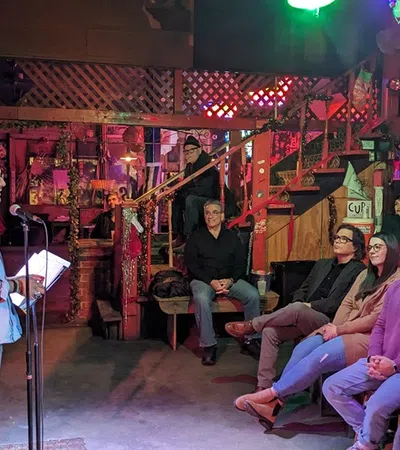 a group of people sitting in a room with a stage and a person standing in front of them