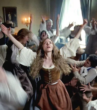Group of 17th century people in period clothing experiencing a frenzied and dramatic seizure-like dance in a dimly lit room