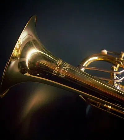 Close-up of golden brass trumpet with visible valves against a dark background and soft lighting highlights.