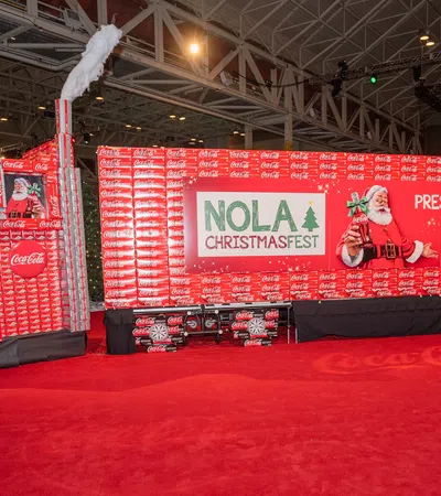 NOLA ChristmasFest display built from Coca-Cola boxes with Santa and snowman decorations indoors.