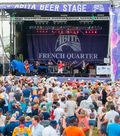 Large crowd enjoying live band performance on Abita Beer Stage at French Quarter Festival outdoors in daytime
