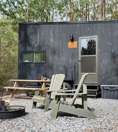 a small cabin with a picnic table and chairs in front of it
