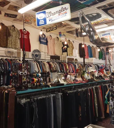 A vintage clothing store interior filled with colorful apparel, accessories, and unique decor items.