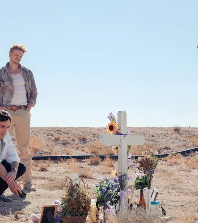 a man and woman kneeling next to a cross with flowers and a cross