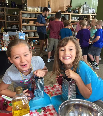 a couple of children sitting at a table with food and drinks