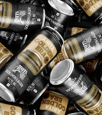 Multiple black and gold Abita Golden Era beer cans scattered in a flat lay arrangement.