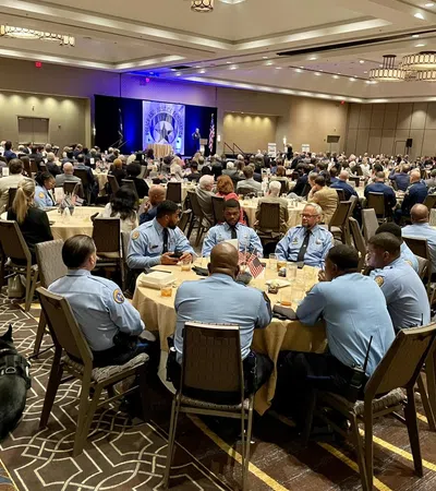 Law enforcement officers in uniform seated at round banquet tables during a formal indoor conference or ceremony.