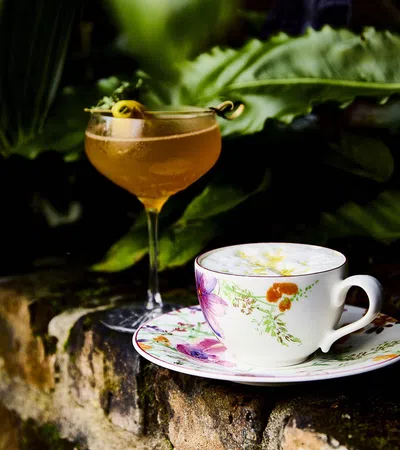 a glass of liquid and a cup of tea on a saucer