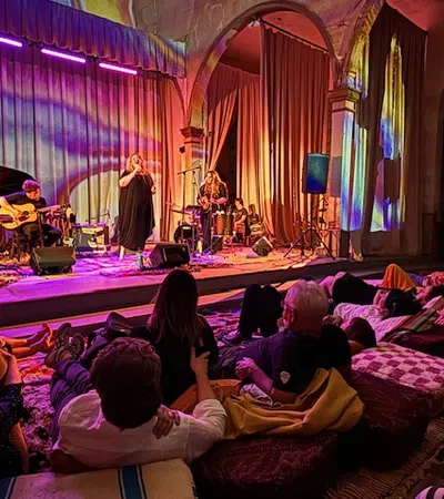 Intimate live music performance with colorful lighting and a cozy audience setting.