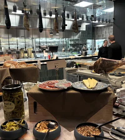 Charcuterie spread with cured meats, cheeses, nuts, pickles, and bread in a modern kitchen setting.