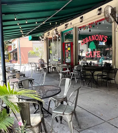 Outdoor seating area at Lebanon's Cafe with metal tables and chairs under green awning on sunny day