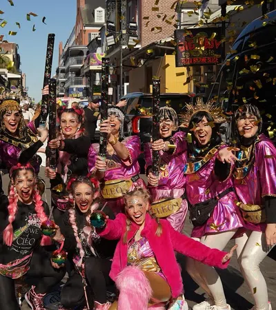 Group of women in colorful costumes celebrating on a city street with confetti and smiles during daytime event