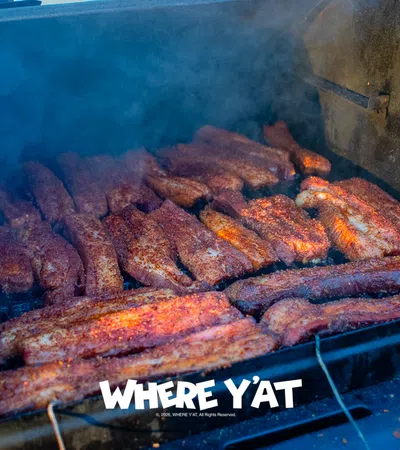 Smoked ribs cooking in a large barbecue smoker with visible smoke and seasoning on the meat