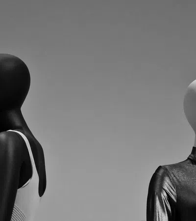 Black and white mannequins wearing contrasting white and black outfits against a gray background.