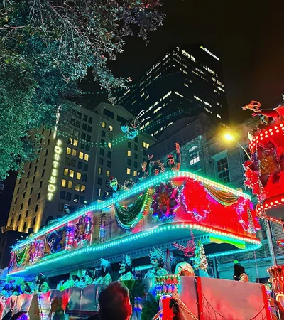 Colorful Mardi Gras parade floats with people in costumes celebrating at night in a city street.