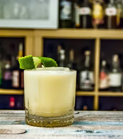 a glass of yellow liquid with a green frog on top