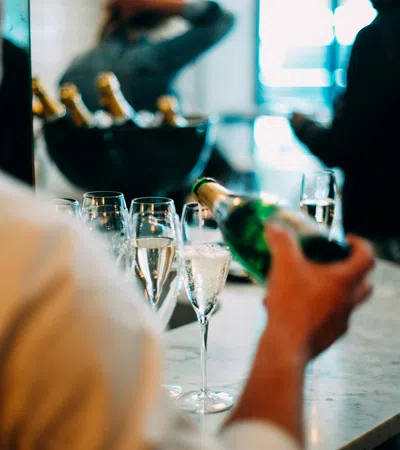 a person pouring wine into glasses