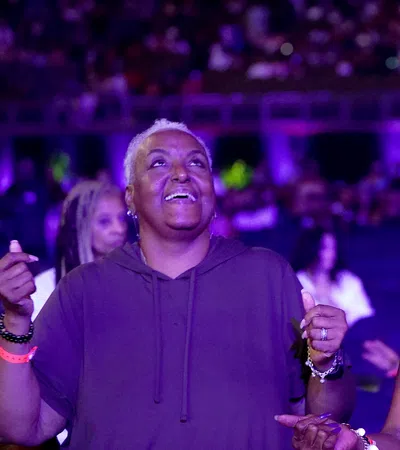 Two women enjoying music, one smiling with eyes closed wearing a cowboy hat, the other with short hair and a hoodie.