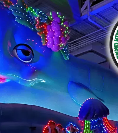 Large blue dolphin float decorated with colorful lights at Bacchus Mardi Gras parade in New Orleans.