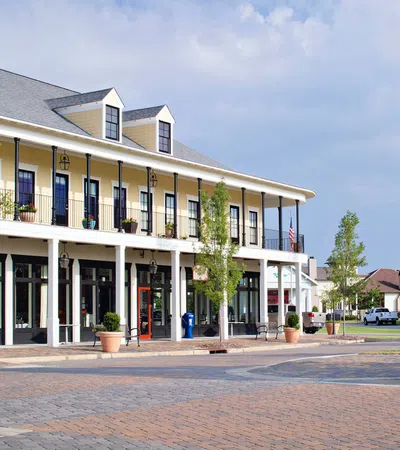 Two-story yellow building with balconies and columns on a cobblestone street in a quiet neighborhood