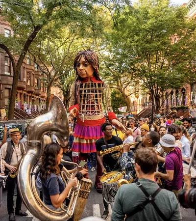 a person in a dress playing a musical instrument in front of a crowd with La Rambla, Barcelona in the background