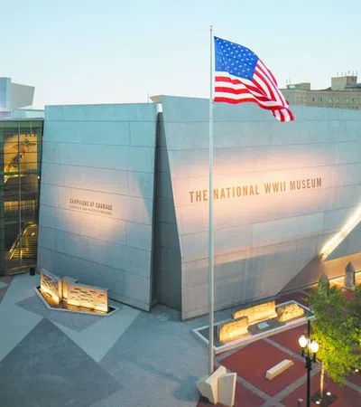 Exterior view of The National WWII Museum with an American flag waving in front during dusk.