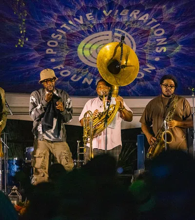 Jazz band performing live on stage with brass instruments under Positive Vibrations Foundation banner.