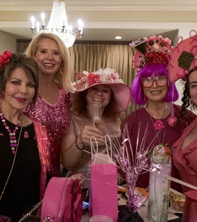 a group of women wearing pink and white hats and posing for a photo