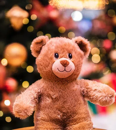 a stuffed bear in front of a christmas tree