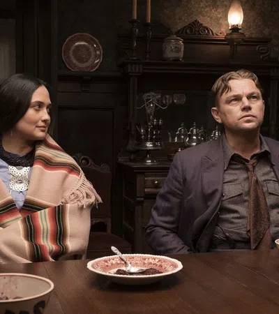 Leonardo DiCaprio, Lily Gladstone sitting at a table with food