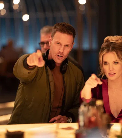 Filmmaker and actress discussing a scene at a stylish bar with drinks and soft lighting.