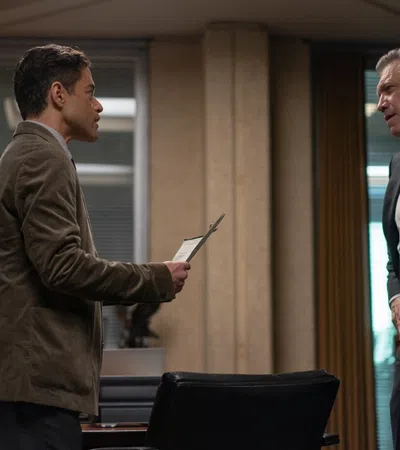 A tense conversation between two men in a modern office setting with contrasting body language.