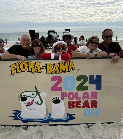 James Bacque et al. on a beach holding a sign