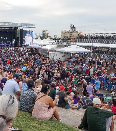 Large crowd enjoying an outdoor concert at the main stage with Chase Rice performing under a cloudy sky.