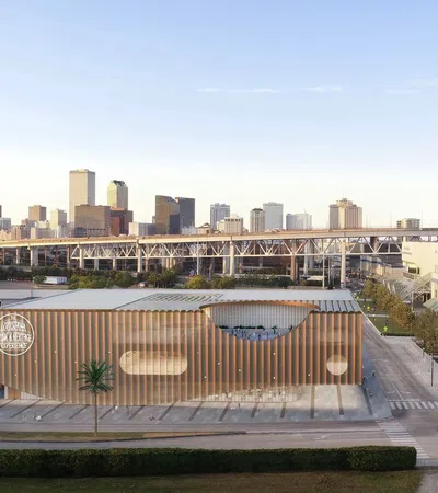 Modern urban building with wooden accents in front of a city skyline and elevated bridge under clear sky.