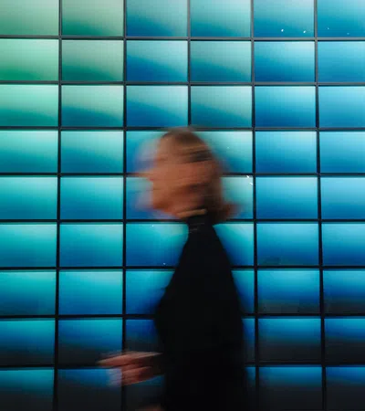 Blurred person walking in front of a vibrant blue tiled wall with gradient lighting