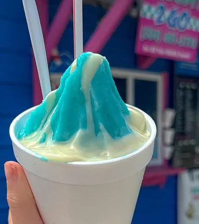 a hand holding a cup of ice cream with a straw