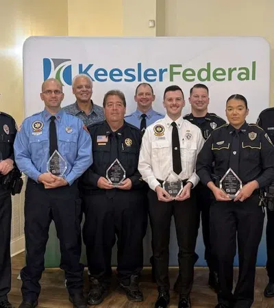 Group of uniformed police and emergency personnel holding awards in front of Keesler Federal backdrop indoors.