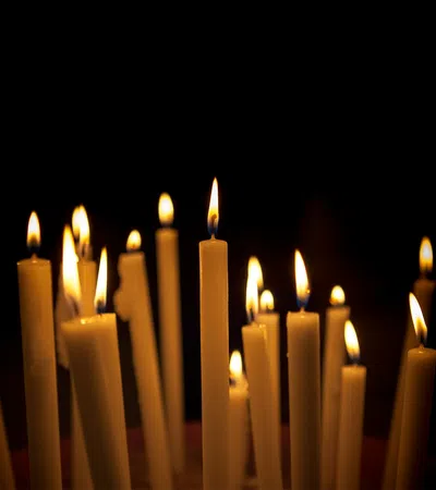 Multiple lit candles glowing against a dark background creating a warm, peaceful ambiance.