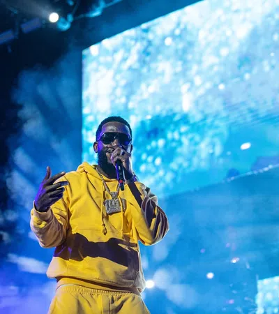 a man wearing a yellow jacket and sunglasses with his hand up