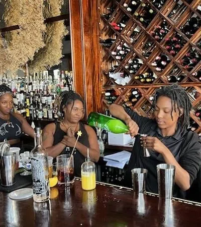 a group of women sitting at a bar drinking from a green bottle
