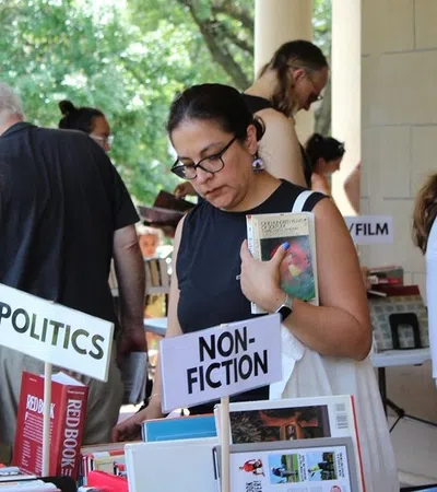 People browsing books at an outdoor book fair with nonfiction and politics sections visible.