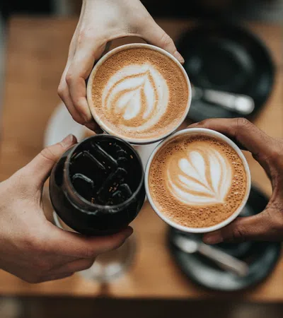 a person holding a couple of coffee cups with foam on them