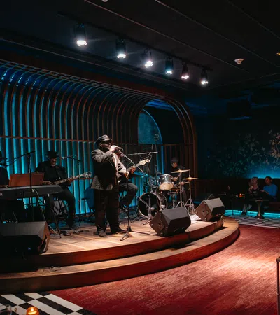 Jazz band performing live on stage in a stylish lounge with blue lighting and cozy seating.