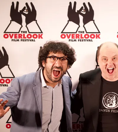 Three excited individuals pose in front of The Overlook Film Festival backdrop.