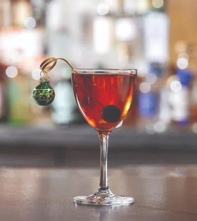 a glass with a red liquid and a green key chain on a wooden surface